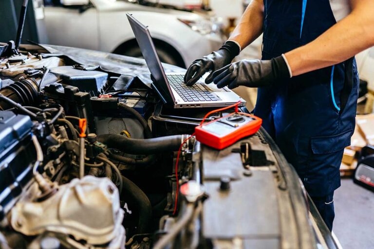 Technician inspecting a car windshield with a visible chip and assessing for possible repair.