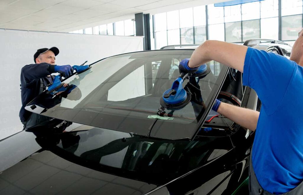 Mechanic checking a vehicle’s tires, battery, fluids, and cooling system in a service bay.
